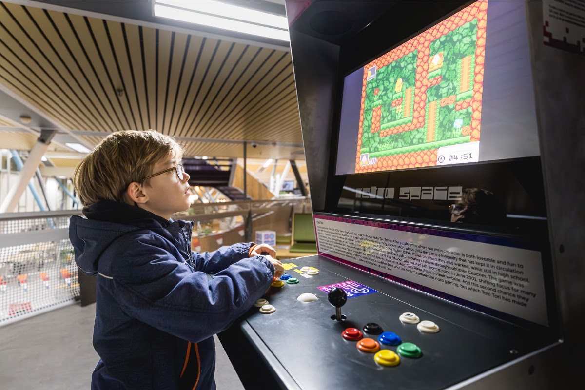 Een jonge jongen speelt een arcade game.
