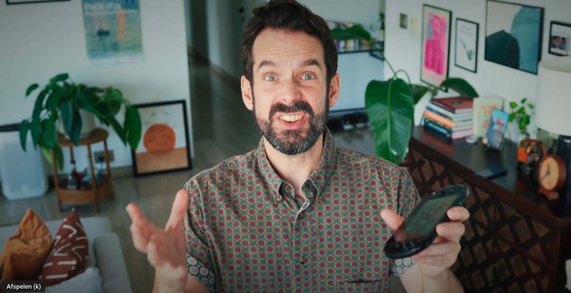 Comedian Simon Feilder in een kamer met een PS Vita in zijn hand