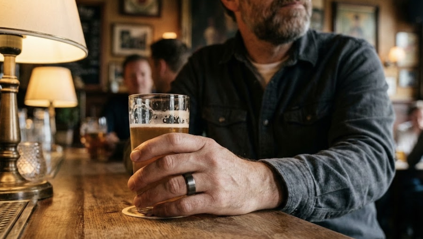Een man drinkt een biertje. Hij heeft een OURA ring subtiel om.