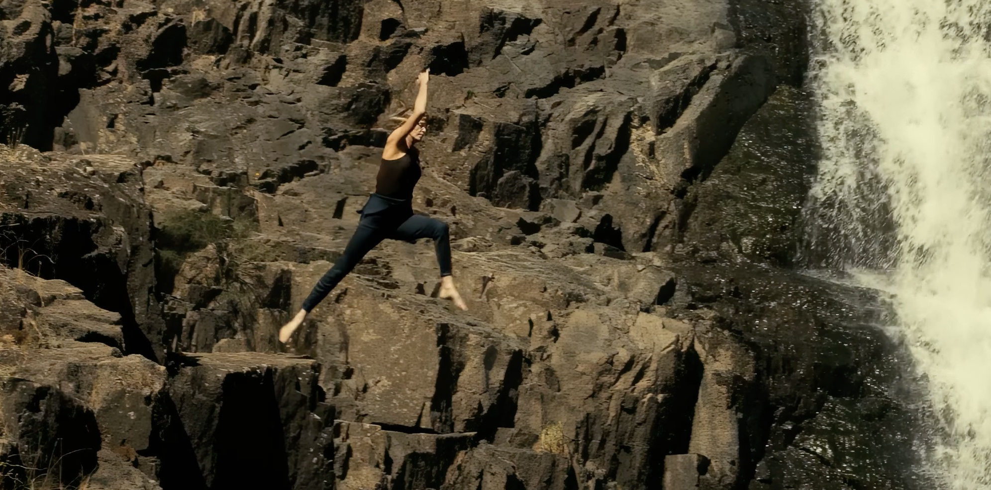 Charlize Theron in Apex. Ze springt van een rots.
