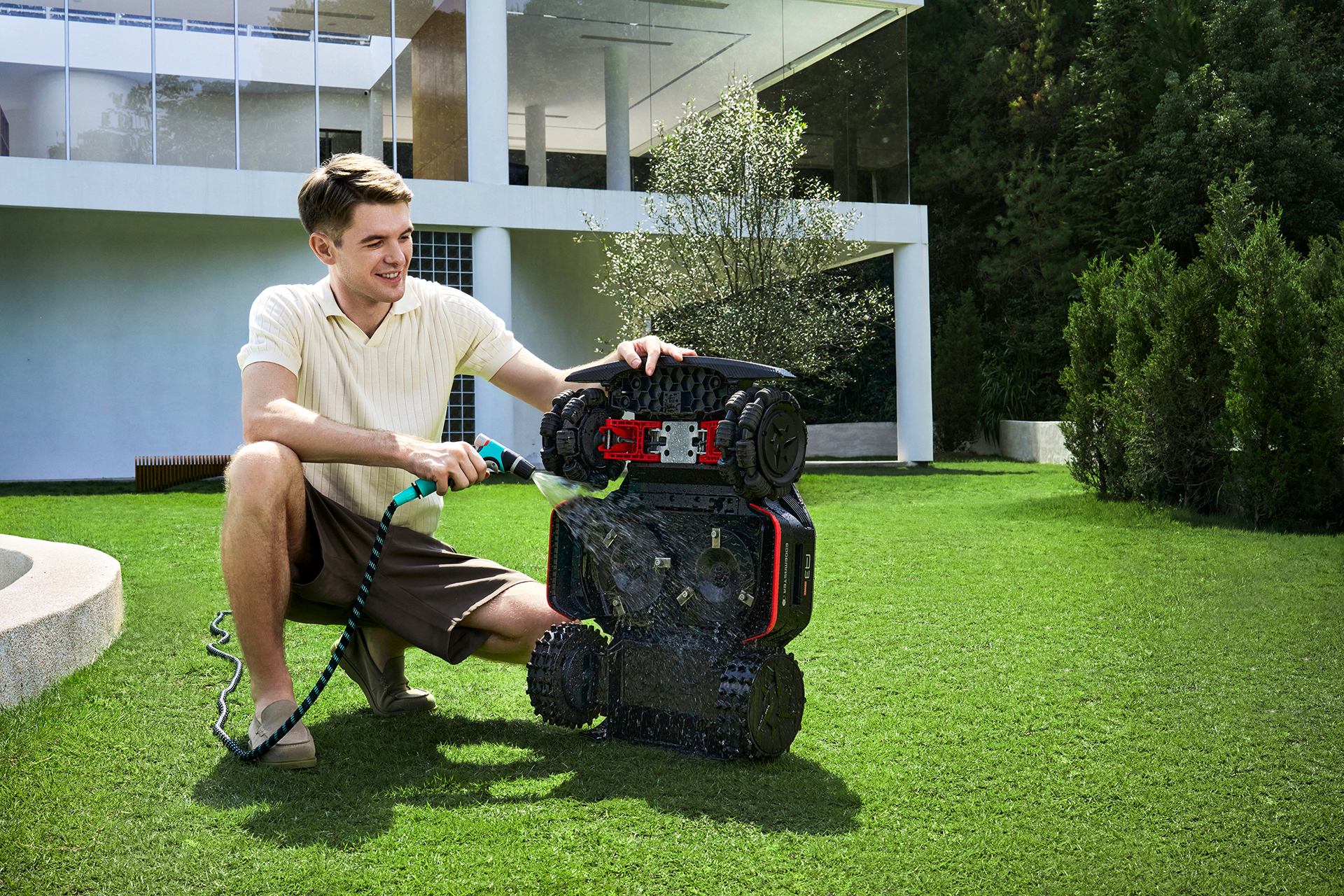 Een man die lacht terwijl hij een grasmaaier aan het natspuiten is. 