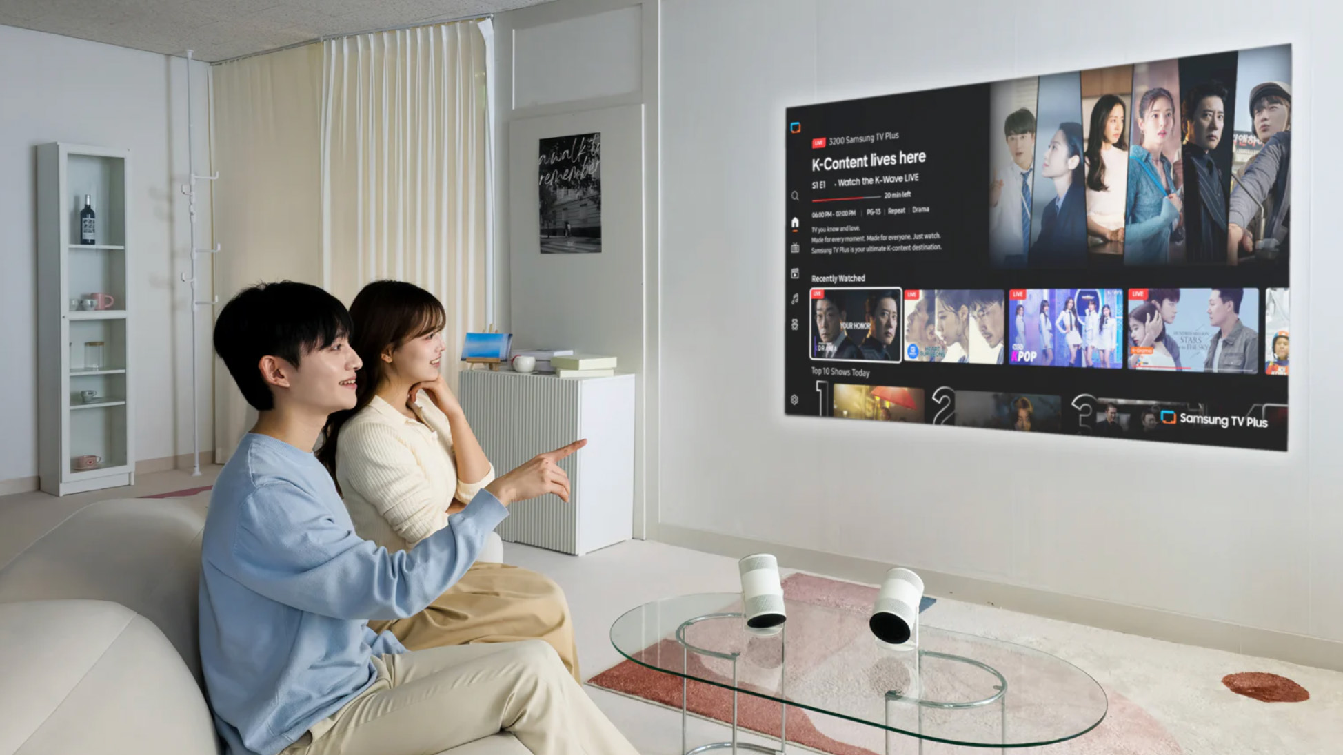 Lifestyleshot van twee mensen met de nieuwe Freestyle+ projector van Samsung. Ze kijken naar een scherm