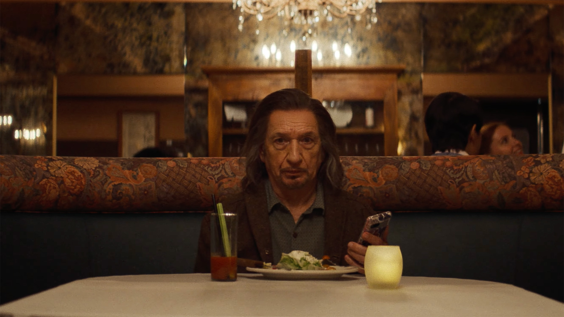 Ben Kingsley in Wonder Man. Hij heeft lang haar en zit op een bankje.